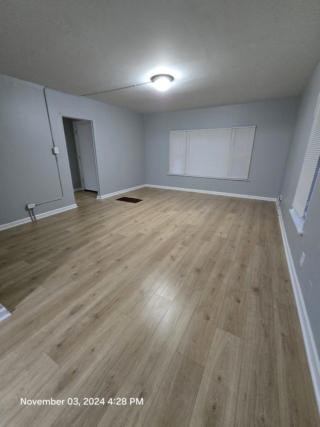 spare room featuring a textured ceiling, wood finished floors, visible vents, and baseboards