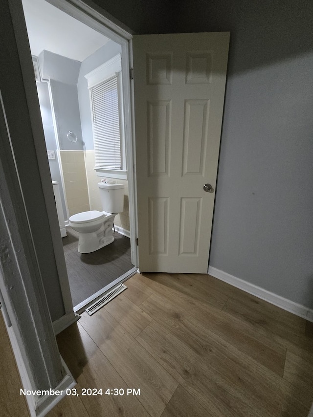 bathroom with baseboards, visible vents, toilet, and wood finished floors