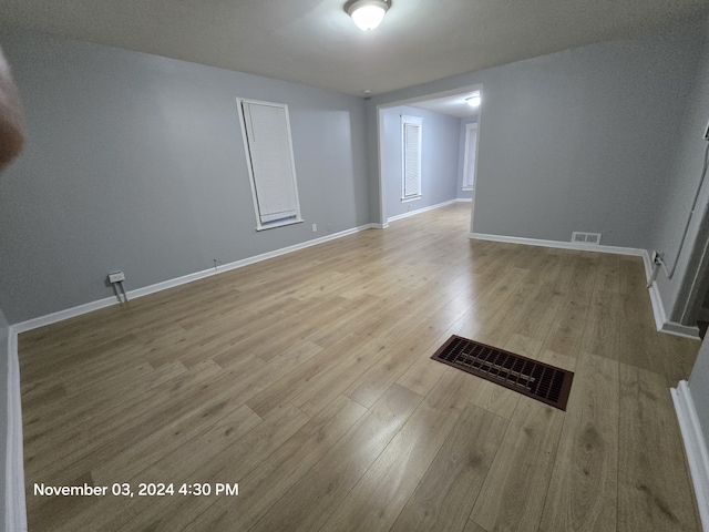 empty room with baseboards, visible vents, and wood finished floors