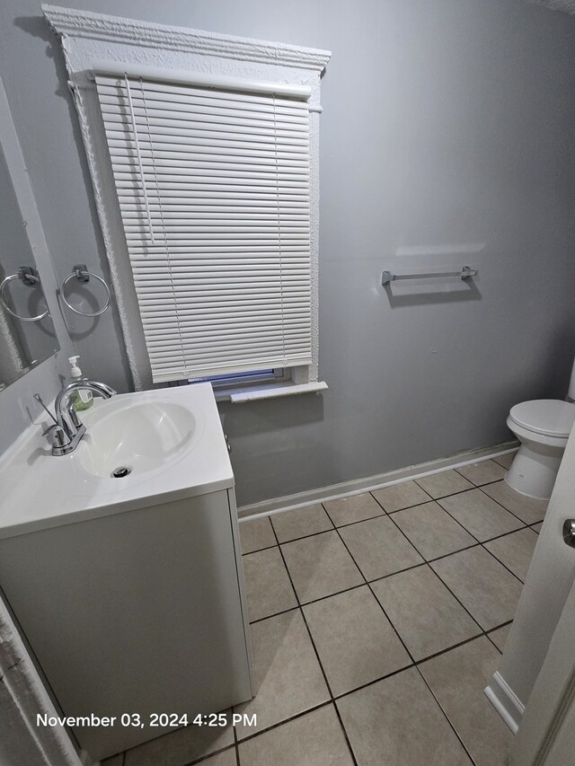 bathroom with tile patterned flooring, baseboards, vanity, and toilet