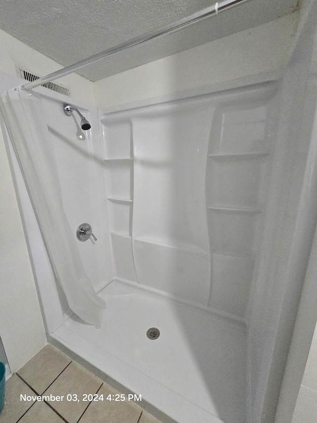 full bathroom featuring tile patterned flooring, a shower stall, and a textured ceiling