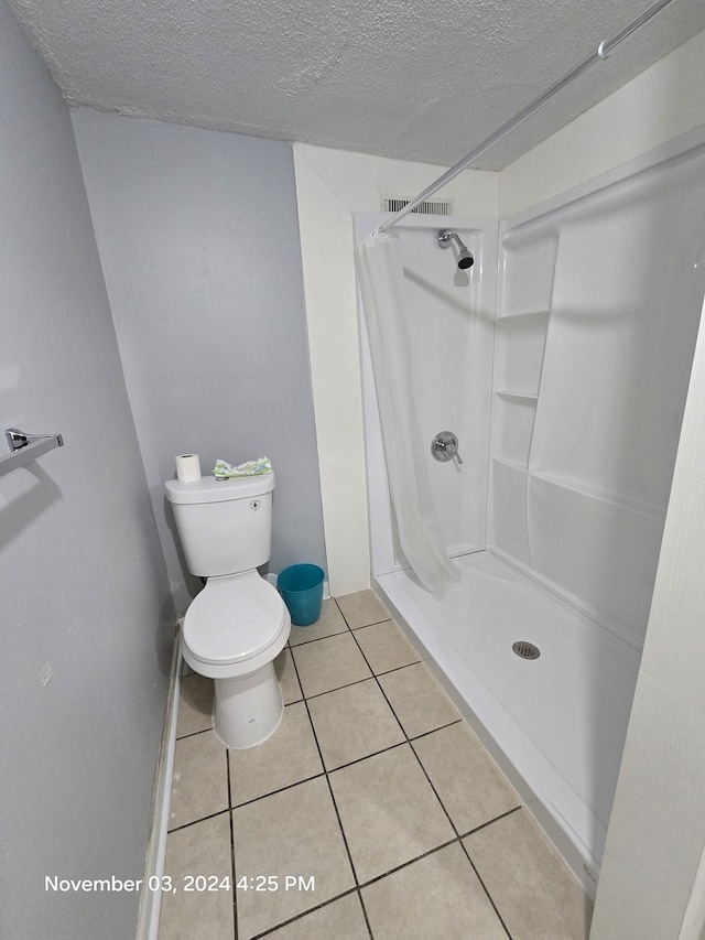 bathroom with a stall shower, tile patterned flooring, visible vents, and a textured ceiling