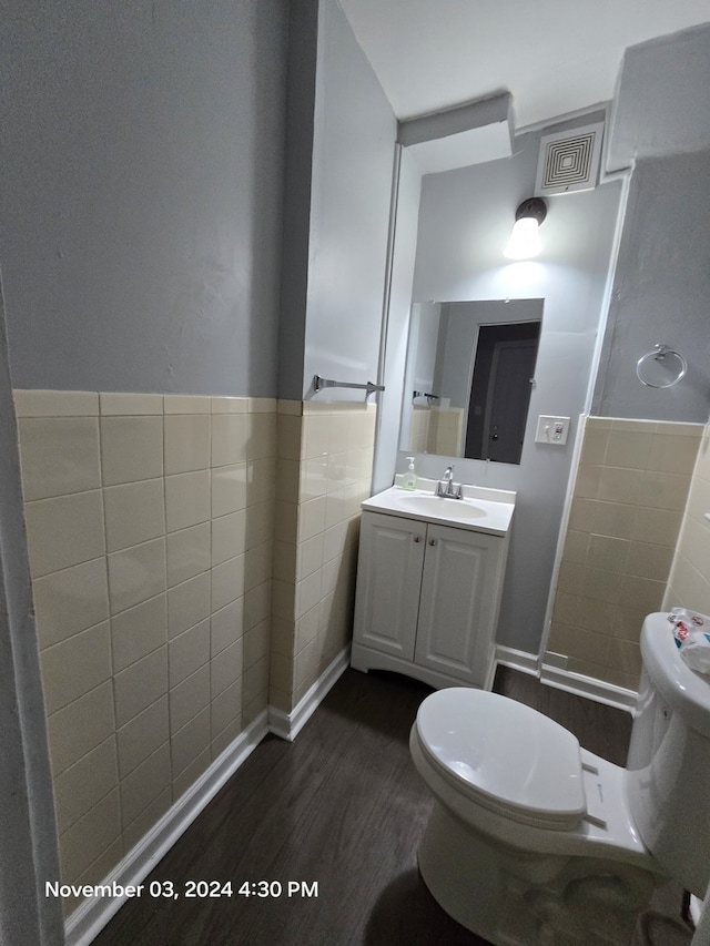 bathroom featuring a wainscoted wall, tile walls, visible vents, toilet, and wood finished floors