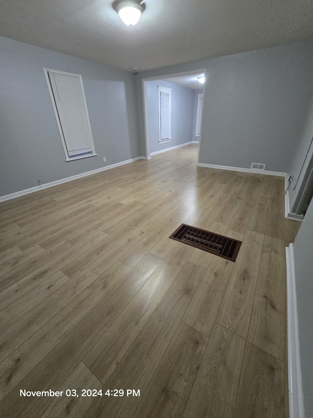 unfurnished room with wood finished floors, visible vents, and baseboards