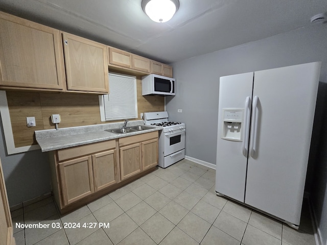 kitchen with white appliances, light countertops, a sink, and light brown cabinetry