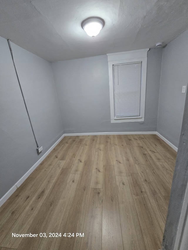 empty room featuring a textured ceiling, baseboards, and wood finished floors