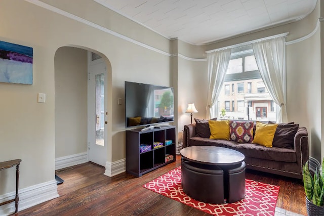 living room featuring arched walkways, visible vents, baseboards, and wood finished floors