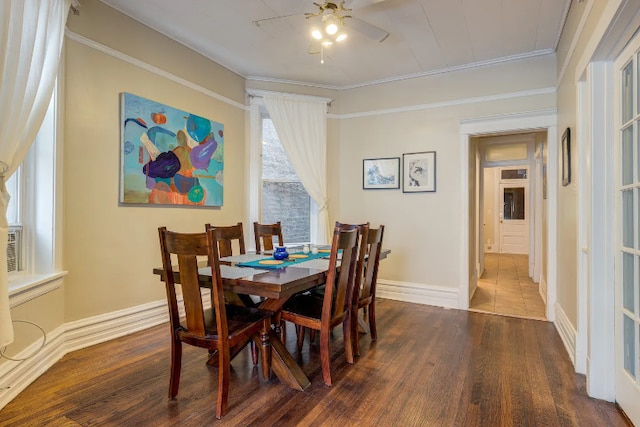 dining area featuring baseboards, dark wood-style flooring, a ceiling fan, and crown molding