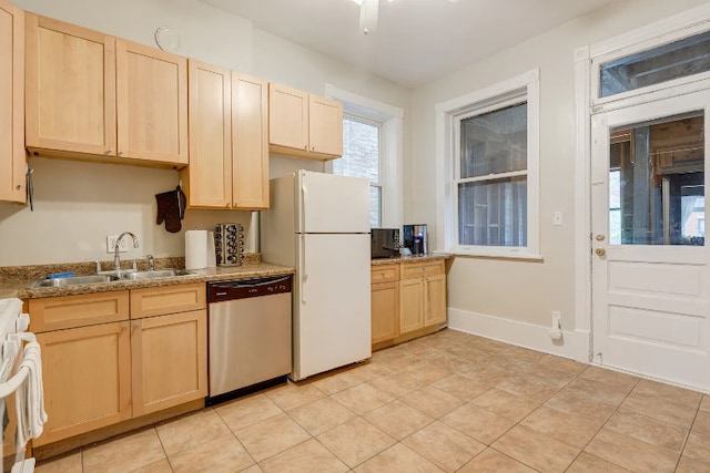 kitchen featuring stainless steel dishwasher, stove, light brown cabinetry, freestanding refrigerator, and a sink