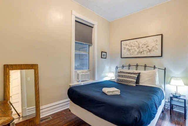 bedroom with baseboards, cooling unit, visible vents, and wood finished floors