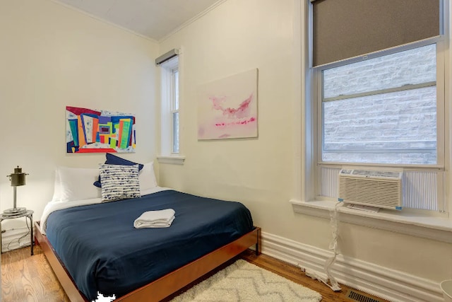 bedroom featuring ornamental molding, cooling unit, wood finished floors, and baseboards