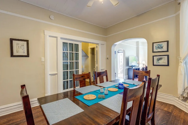 dining space featuring arched walkways, wood finished floors, and crown molding