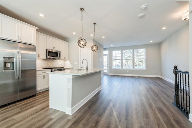 kitchen featuring a kitchen island with sink, stainless steel appliances, dark wood-style flooring, white cabinets, and tasteful backsplash