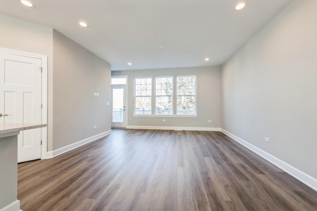 unfurnished living room featuring baseboards, dark wood-type flooring, and recessed lighting