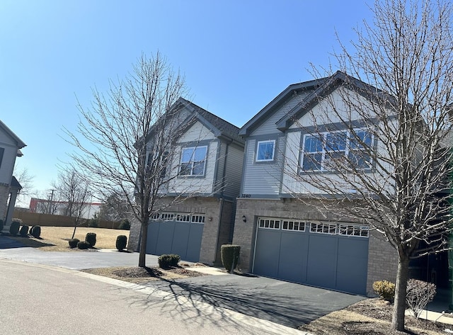 view of front of home with driveway, a garage, and brick siding