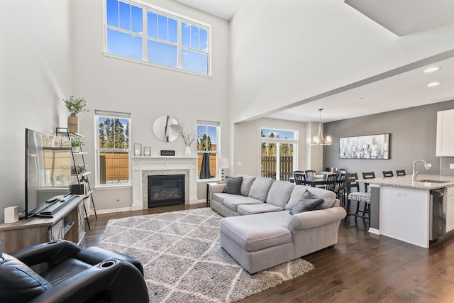 living room with dark wood-style floors, a chandelier, a glass covered fireplace, and baseboards