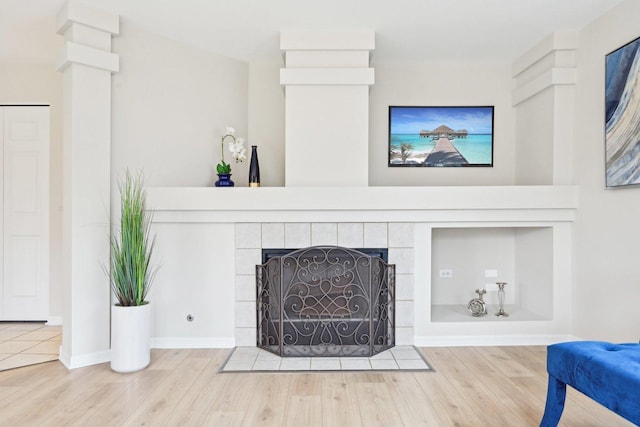 interior details with baseboards, wood finished floors, and a tile fireplace