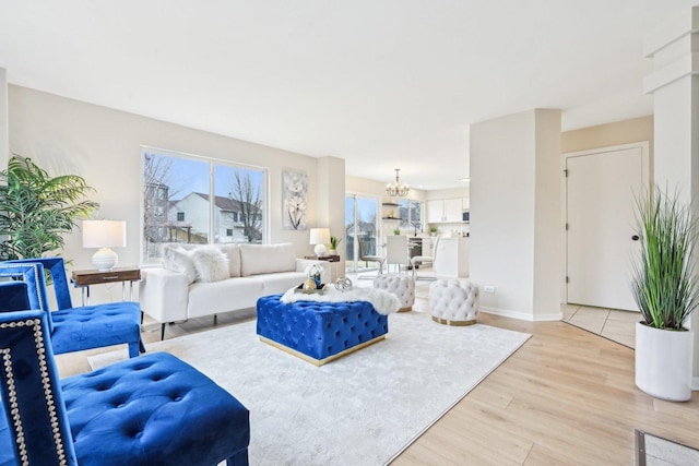 living room with light wood-style floors, baseboards, and a notable chandelier