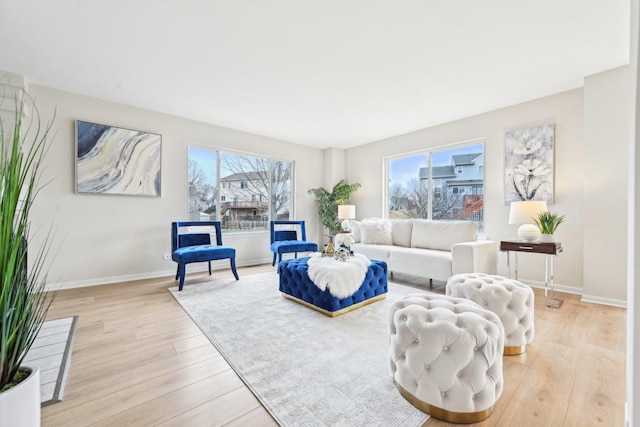 living room featuring baseboards, a healthy amount of sunlight, and light wood finished floors