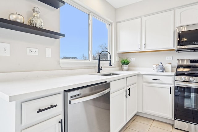 kitchen with light tile patterned floors, white cabinets, appliances with stainless steel finishes, open shelves, and a sink