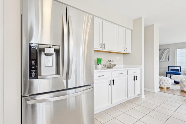 kitchen with white cabinets, light tile patterned floors, stainless steel fridge, and light countertops