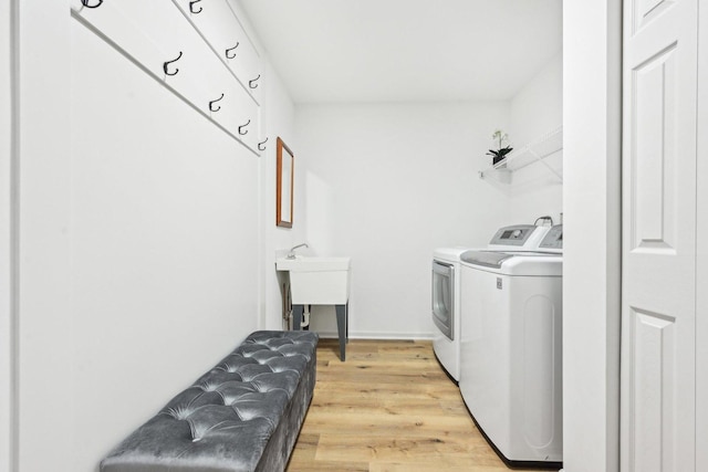 laundry area with light wood-type flooring, washer and dryer, laundry area, and a sink