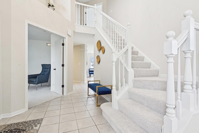 stairs featuring baseboards, a high ceiling, and tile patterned floors