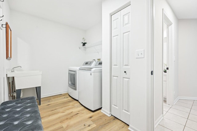 clothes washing area with laundry area, washer and clothes dryer, light wood-type flooring, and baseboards