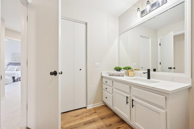 ensuite bathroom featuring vanity, ensuite bath, and wood finished floors