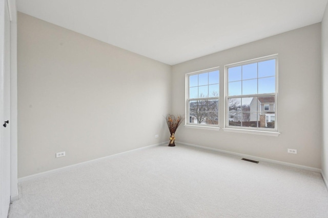 empty room with carpet, visible vents, and baseboards