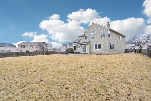 back of house with a chimney, a fenced backyard, and a lawn