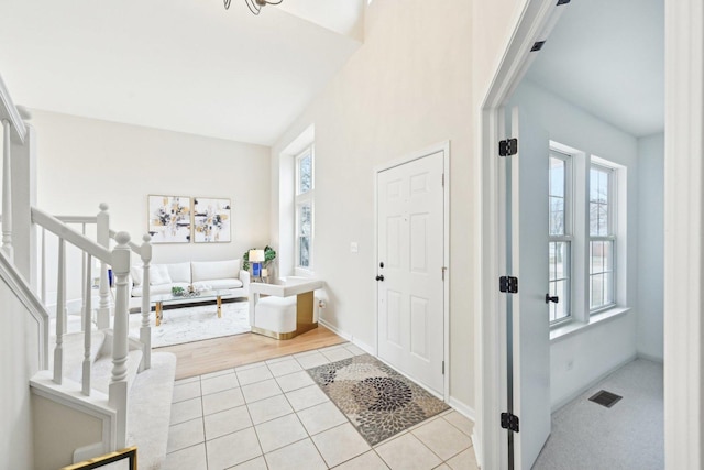 foyer featuring a healthy amount of sunlight, light tile patterned floors, stairway, and visible vents