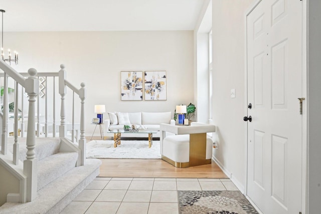 foyer entrance with light tile patterned floors, baseboards, stairway, and a chandelier