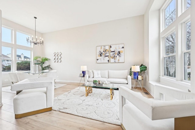 living room featuring a notable chandelier, baseboards, and wood finished floors