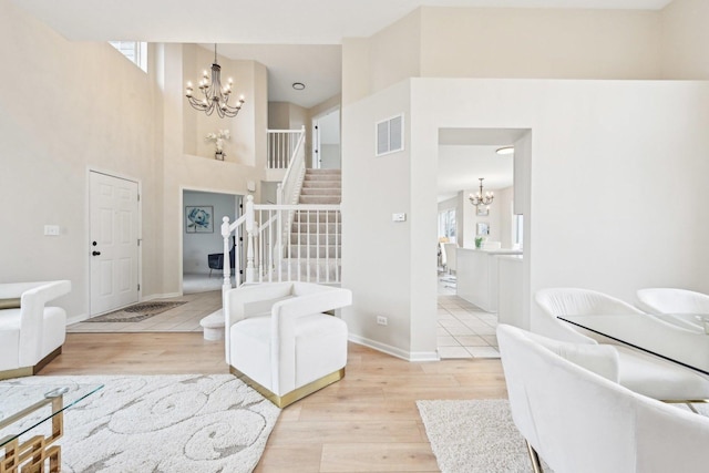 foyer with an inviting chandelier, stairs, visible vents, and wood finished floors