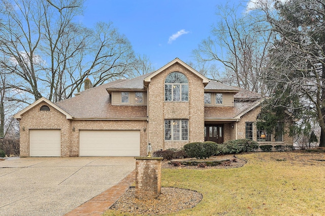 traditional-style home featuring concrete driveway, a chimney, an attached garage, a front yard, and brick siding