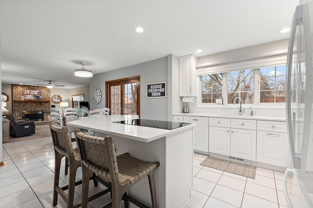 kitchen with light tile patterned floors, a sink, a breakfast bar area, and black electric cooktop