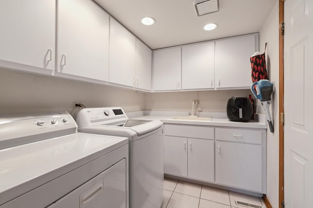 laundry room with light tile patterned floors, cabinet space, washing machine and clothes dryer, a sink, and recessed lighting