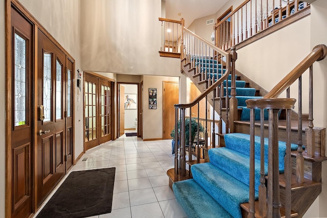 tiled entrance foyer featuring a towering ceiling, baseboards, visible vents, and french doors