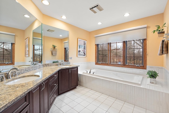 bathroom featuring a bath, visible vents, a sink, and tile patterned floors