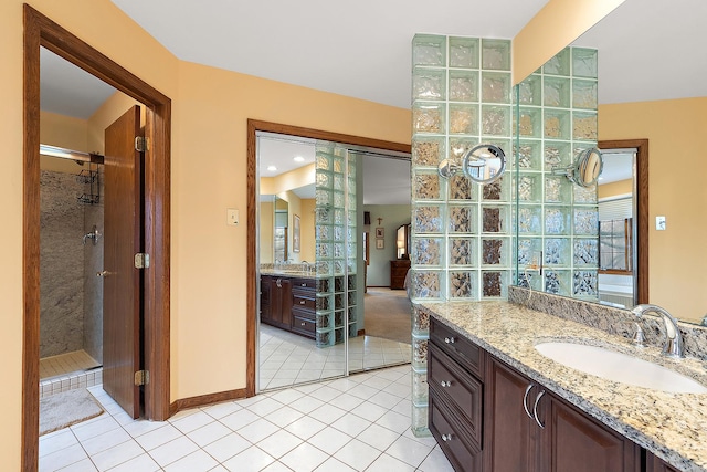 bathroom with a tile shower, two vanities, tile patterned flooring, and a sink