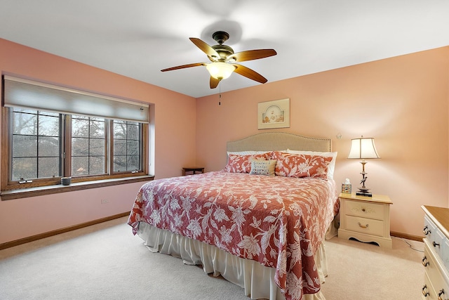 bedroom with a ceiling fan, light carpet, and baseboards