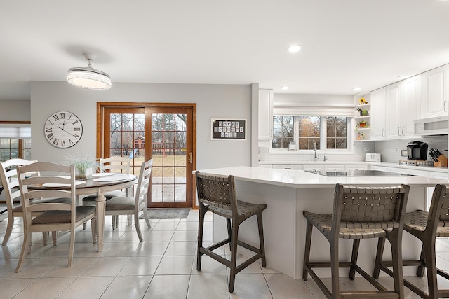 kitchen featuring light countertops, white microwave, a wealth of natural light, and tasteful backsplash