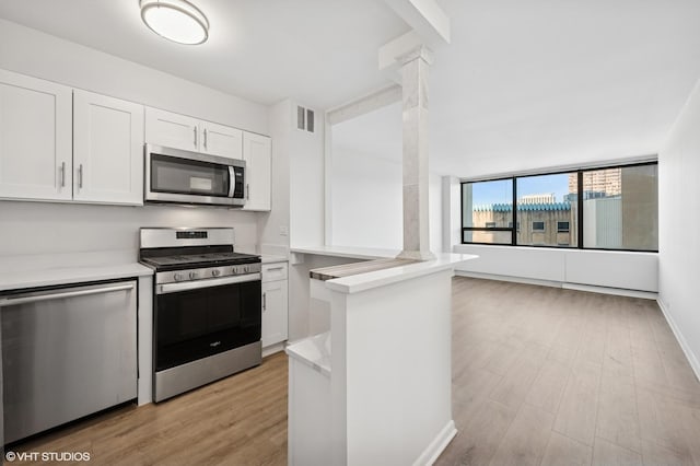 kitchen with visible vents, decorative columns, stainless steel appliances, light countertops, and white cabinetry