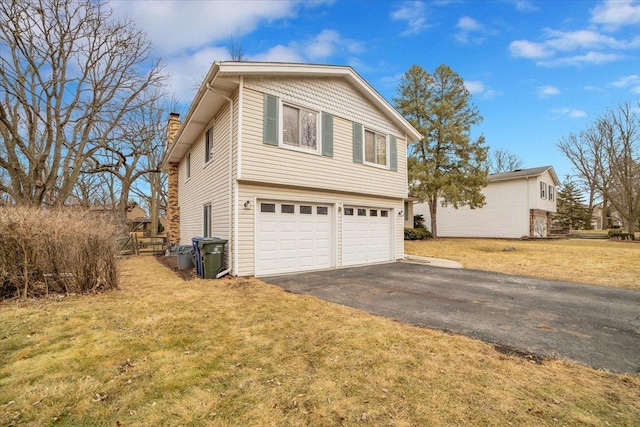 view of side of home featuring a garage, driveway, a chimney, and a lawn