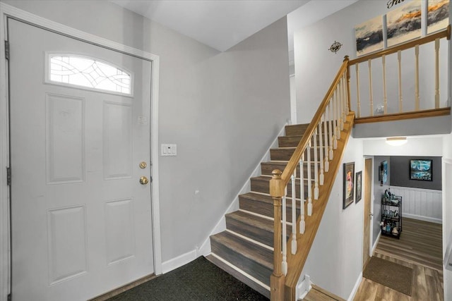 foyer entrance with stairway, wood finished floors, and baseboards