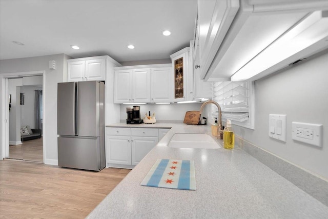 kitchen featuring recessed lighting, a sink, white cabinets, light countertops, and freestanding refrigerator