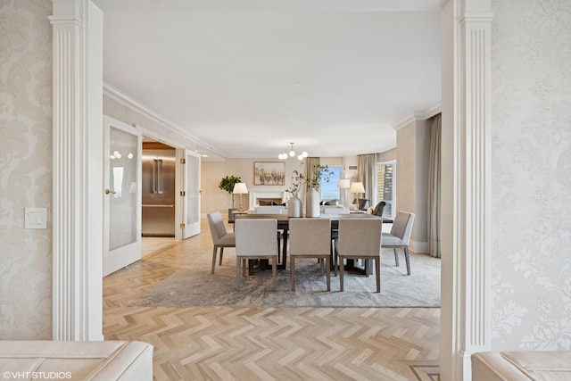 dining space with wallpapered walls, decorative columns, baseboards, and crown molding