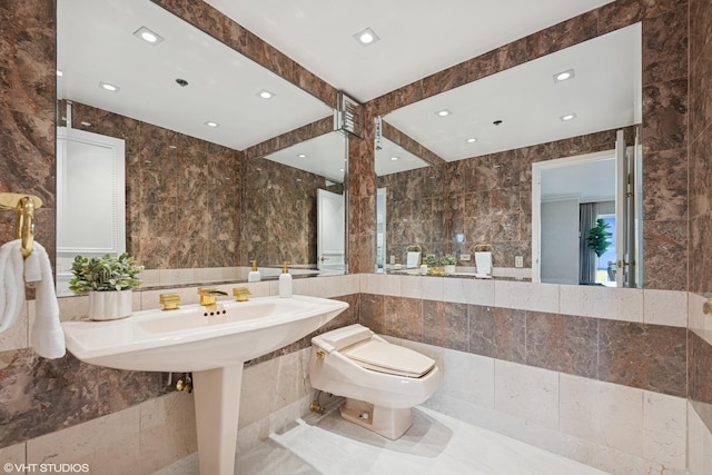 bathroom with recessed lighting, tile walls, and toilet