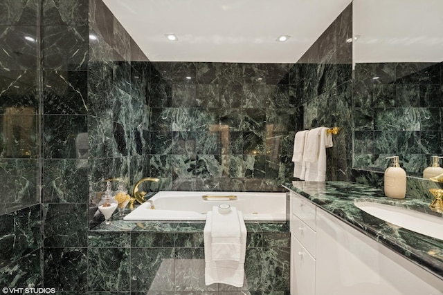 bathroom featuring a bath, vanity, and tile walls